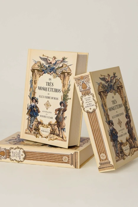 Exemplares de Os Três Mosqueteiros em pé e deitados, mostrando a capa e a lombada ilustradas
